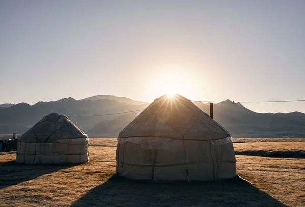 Yurt nomadic houses camp at mountain valley at sunrise in Central Asia