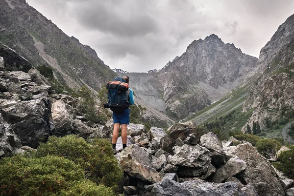 带着大背包的游客在吉尔吉斯斯坦卡拉科尔国家公园的高山谷地的石道上 — 图库照片