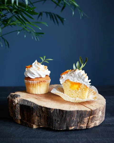 Homemade lemon cupcakes decorated with lemon and leaves on dark blue background.