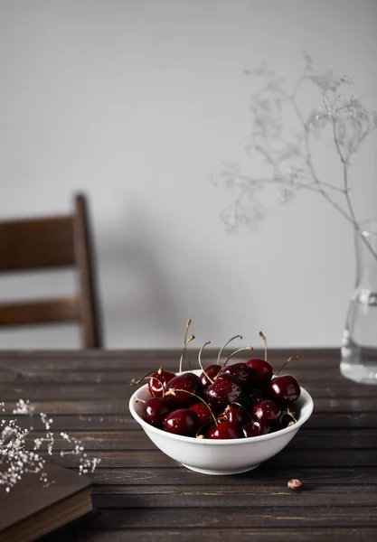 Svart Körsbär Den Vita Skålen Träbordet Nära Vita Blommor Och — Stockfoto