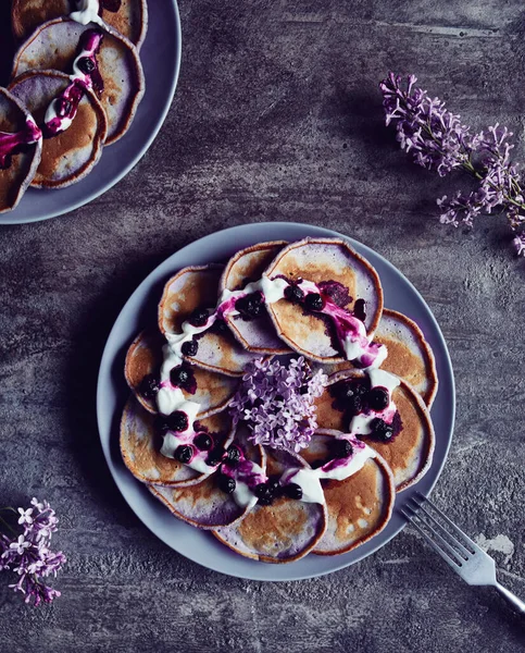 春は薄紫色の花で飾られたブルーベリーとクリームのバイオレットパンケーキ — ストック写真
