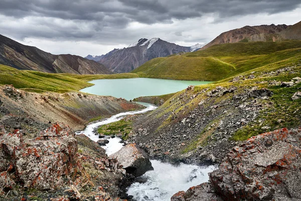 Beautiful scenery of the river and Lake Teshik Kol the mountain valley at dramatic cloudy sky in Kyrgyzstan