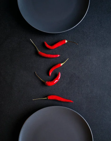 Siyah Masadaki Iki Seramik Tabağın Arasındaki Kırmızı Biberin Minimalist Kompozisyonu — Stok fotoğraf
