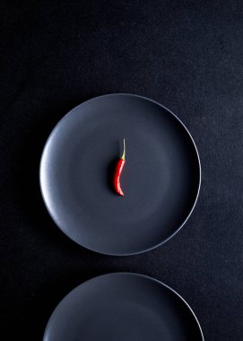 Siyah masada siyah seramik tabakta kırmızı biberin minimalist kompozisyonu