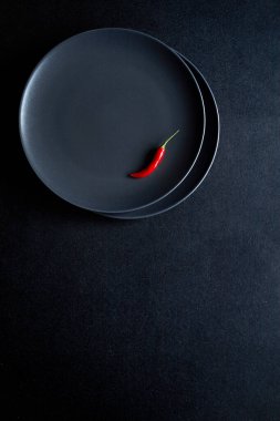 Siyah masadaki seramik tabakta kırmızı biber minimalist kompozisyonu