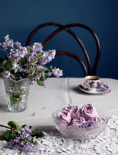 薄紫色の花の近くの黒いスグリから大気中の紫色の甘い自家製ゼファーまたはマシュマロ灰色のテーブルクロスと暗い背景のコーヒーカップ — ストック写真