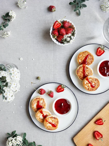 自制的乌克兰奶酪煎饼西尔尼奇 桌布上方白花附近有红色草莓果酱和浆果 — 图库照片