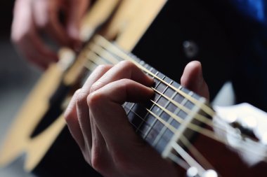 Adamın elleri akustik gitar çalıyor.