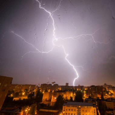 Bulutlar ve gök gürültüsü Lightning'ler ve şehir üzerinde fırtına. Damla ile cam