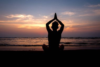 Gün batımında sahilde Yoga uygulamak genç sağlıklı adam