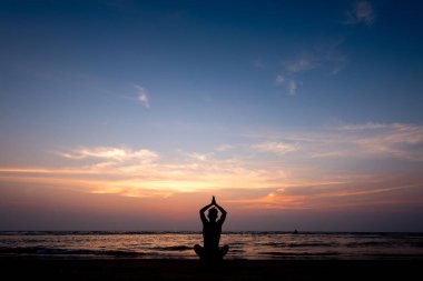 Gün batımında sahilde Yoga uygulamak genç sağlıklı adam