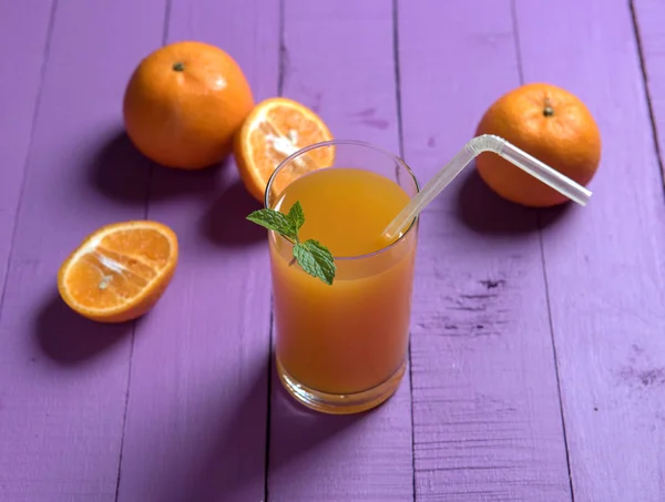 Orangensaft auf violettem Hintergrund — Stockfoto
