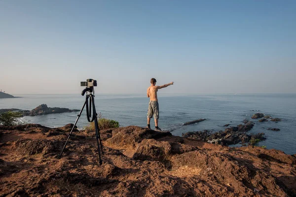 video blogger outside. shoots video with a tripod over sea.