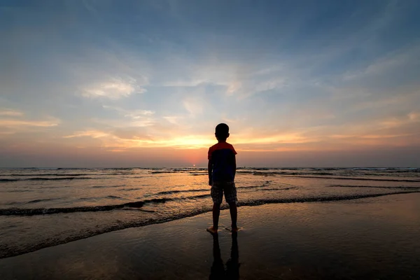 Garçon regardant coucher de soleil sur la plage, coucher de soleil coloré — Photo