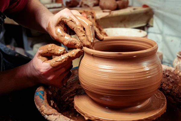 Potter at work. Workshop. Hands of a potter, creating an earthen jar on the circle — Stock Photo, Image