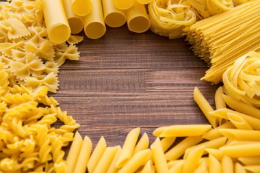 Ahşap arka plan üzerinde makarna çeşitleri. Farfalle, fettuccine, erişte, düdük ve penne rigate. Lezzetli İtalyan yemekleri.