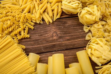 Ahşap arka plan üzerinde makarna çeşitleri. Farfalle, fettuccine, erişte, düdük ve penne rigate