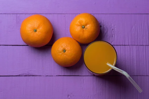 Jus d'orange op violette achtergrond — Stockfoto