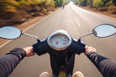 Scooter sürüş bir asfalt yolda binici. Bulanık hareket backgro