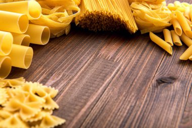 Ahşap arka plan üzerinde makarna çeşitleri. Farfalle, fettuccine, erişte, düdük ve penne rigate