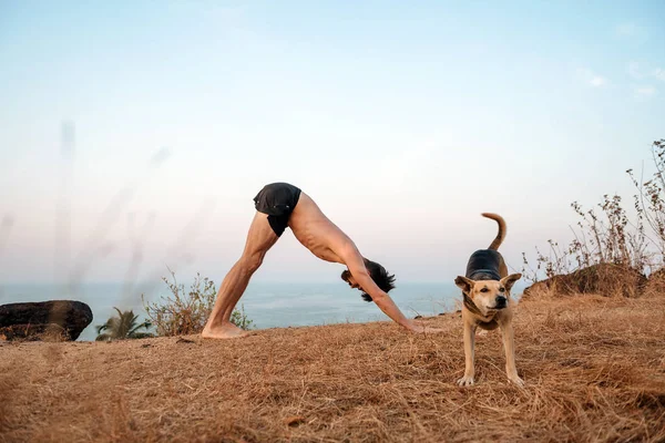 Gesunder Mann praktiziert Yoga unter dem Strand bei Sonnenuntergang. — Stockfoto