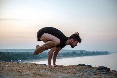 Sağlıklı adam gün batımında Yoga plaj altında uygulamak.