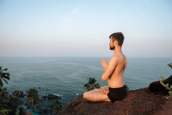 Gezonde man beoefenen van yoga onder het strand bij zonsondergang. — Stockfoto