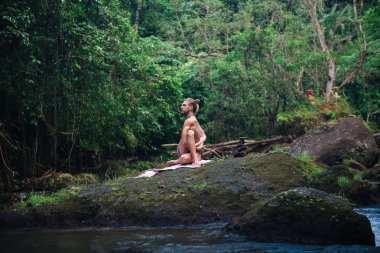 Yoga uygulaması ve doğada meditasyon. Nehir yakınlarında pratik yapan adam
