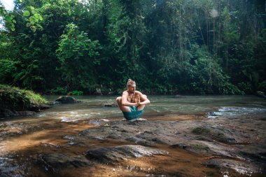 Yoga uygulaması ve doğada meditasyon. Nehir yakınlarında pratik yapan adam