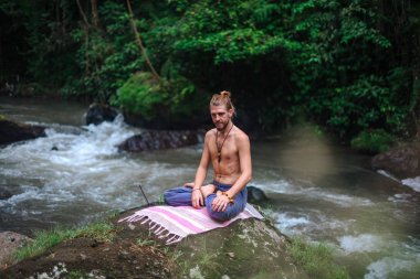 Yoga uygulaması ve doğada meditasyon. Nehir yakınlarında pratik yapan adam
