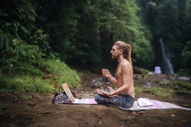 Yoga uygulaması ve doğada meditasyon. Nehir yakınlarında pratik yapan adam