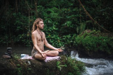 Yoga uygulaması ve doğada meditasyon. Nehir yakınlarında pratik yapan adam