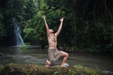 Yoga uygulaması ve doğada meditasyon. Nehir yakınlarında pratik yapan adam