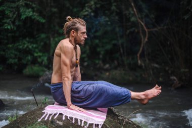 Yoga uygulaması ve doğada meditasyon. Nehir yakınlarında pratik yapan adam