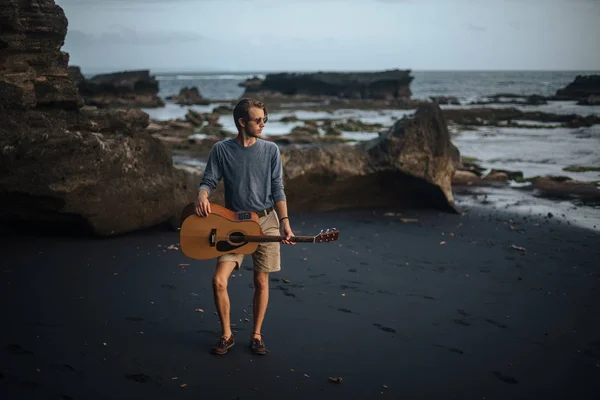 Romantische jongeman met een gitaar op het strand — Stockfoto