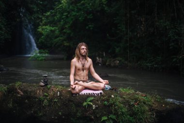 Yoga uygulaması ve doğada meditasyon. Nehir yakınlarında pratik yapan adam