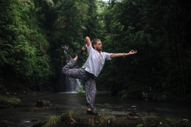 Yoga uygulaması ve doğada meditasyon. Nehir yakınlarında pratik yapan adam