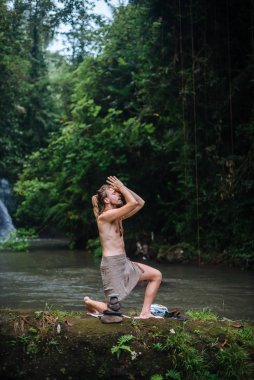 Yoga uygulaması ve doğada meditasyon. Nehir yakınlarında pratik yapan adam