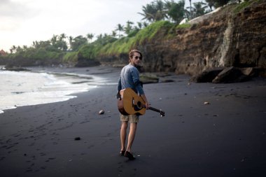 Sahilde gitar çalan romantik bir genç adam.