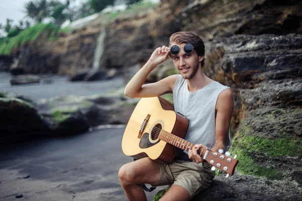Joven romántico con una guitarra en la playa — Foto de Stock