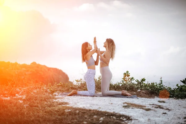 Coppia di ragazze pratica yoga sullo sfondo dell'oceano — Foto Stock