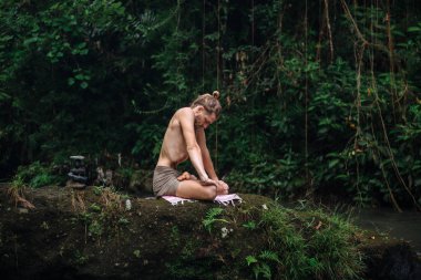 Yoga uygulaması ve doğada meditasyon. Nehir yakınlarında pratik yapan adam