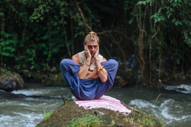 Yoga uygulaması ve doğada meditasyon. Nehir yakınlarında pratik yapan adam