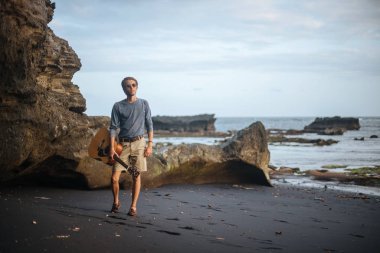 Sahilde gitar çalan romantik bir genç adam.