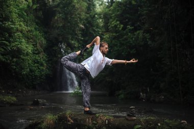 Yoga uygulaması ve doğada meditasyon. Nehir yakınlarında pratik yapan adam