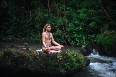 Yoga uygulaması ve doğada meditasyon. Nehir yakınlarında pratik yapan adam