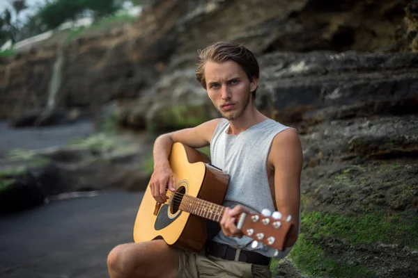 Romantic young man with a guitar on the beach — Stock Photo, Image