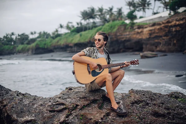 Romantische jongeman met een gitaar op het strand — Stockfoto