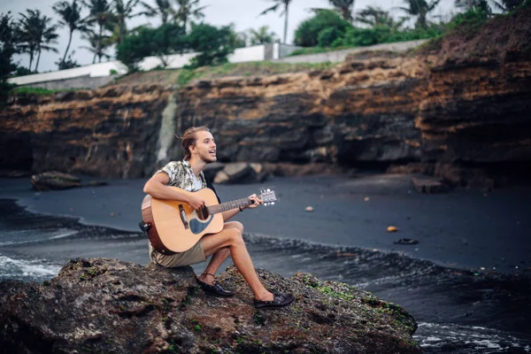 Romantische jongeman met een gitaar op het strand — Stockfoto