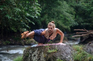Yoga uygulaması ve doğada meditasyon. Nehir yakınlarında pratik yapan adam